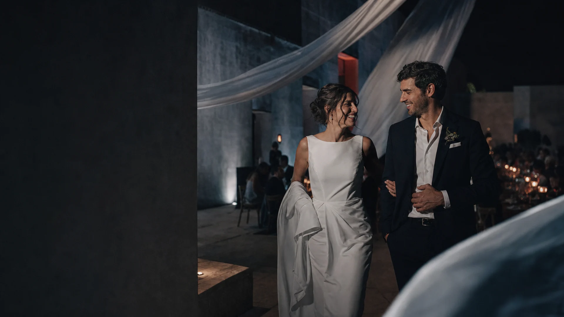 Newlywed couple walking through an evening reception